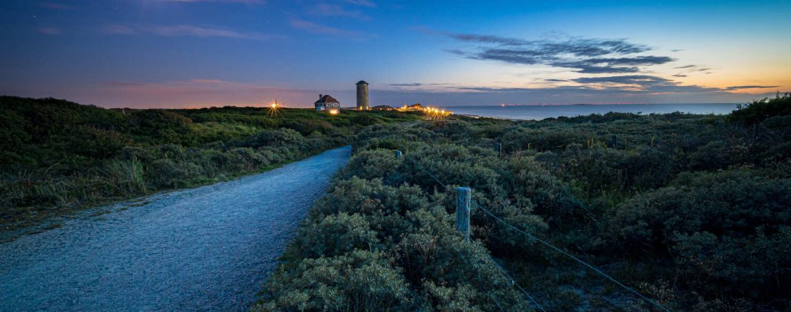 caminho-cercado-por-arbustos-e-vegetacao-que-leva-um-povoado-e-um-mar-ao-por-sol